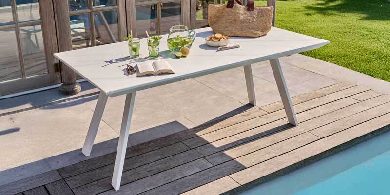 Mesa de jardín de aluminio y piedra junto a una piscina